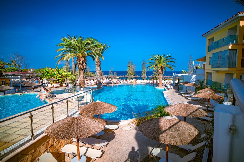 Pool with thatched umbrellas and sea, Malama Beach Holiday Village