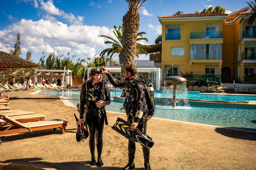 Two divers in wetsuits walking through the gardens to the beach at Malama Beach Holiday Village