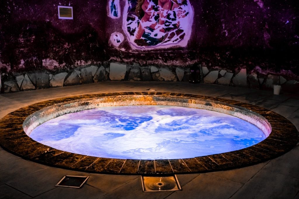 Lit jacuzzi set into the rock in the wellness area at Malama Beach Holiday Village, Protaras